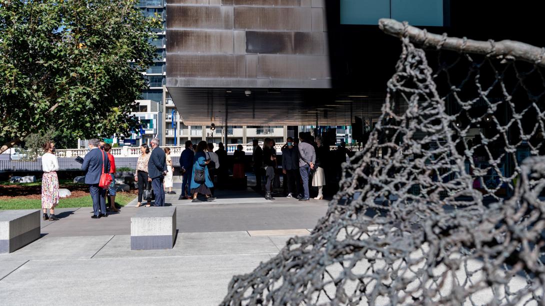 A close-up detail view of a sculptural work installed outside GOMA, with people crowded in the background for an event.