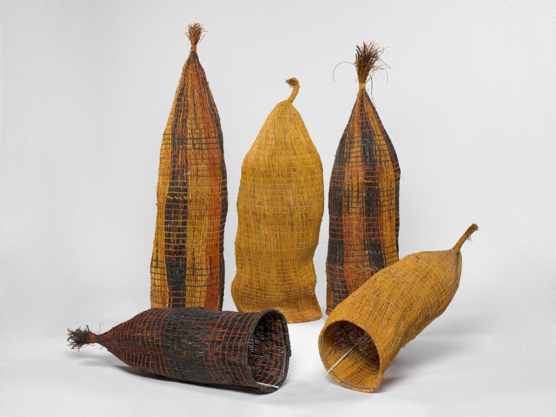 A cropped installation view of five woven fish traps made in varying earth-tones.