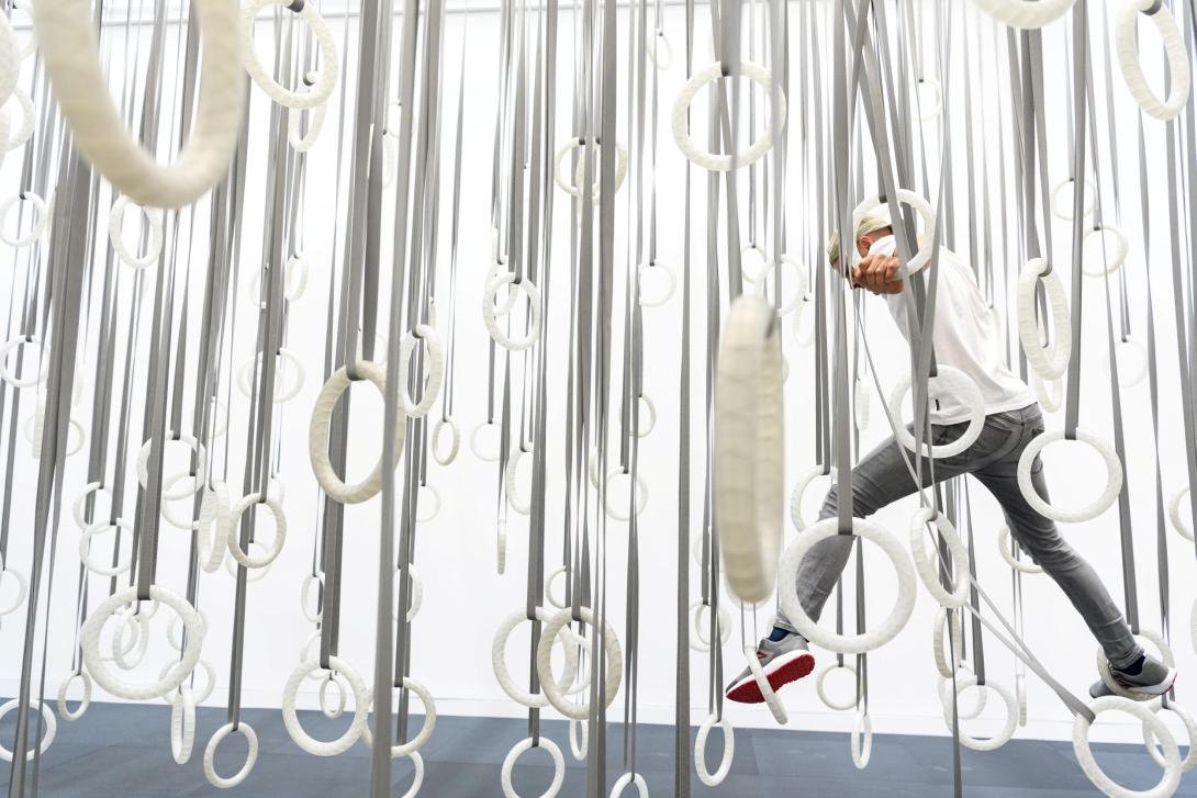 An installation view of an artwork made of suspended hoops that can be used to climb across the artwork itself.