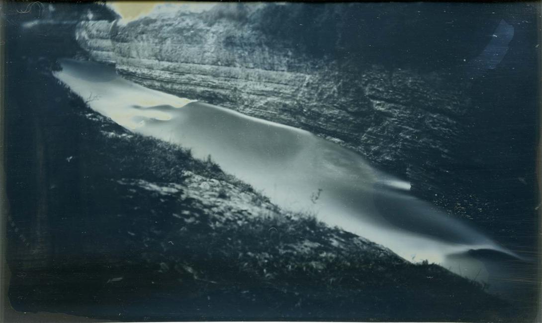 A grey-toned photograph of a river running through a ravine.