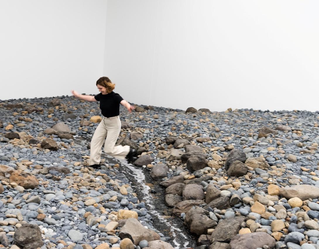 An installation view that appears to be a room-sized riverbed that visitors can traverse and scramble over.