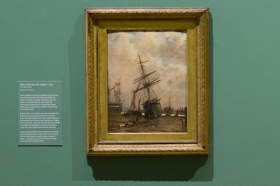 An installation view of an oil painting of a ship hung on a sage-green gallery wall.