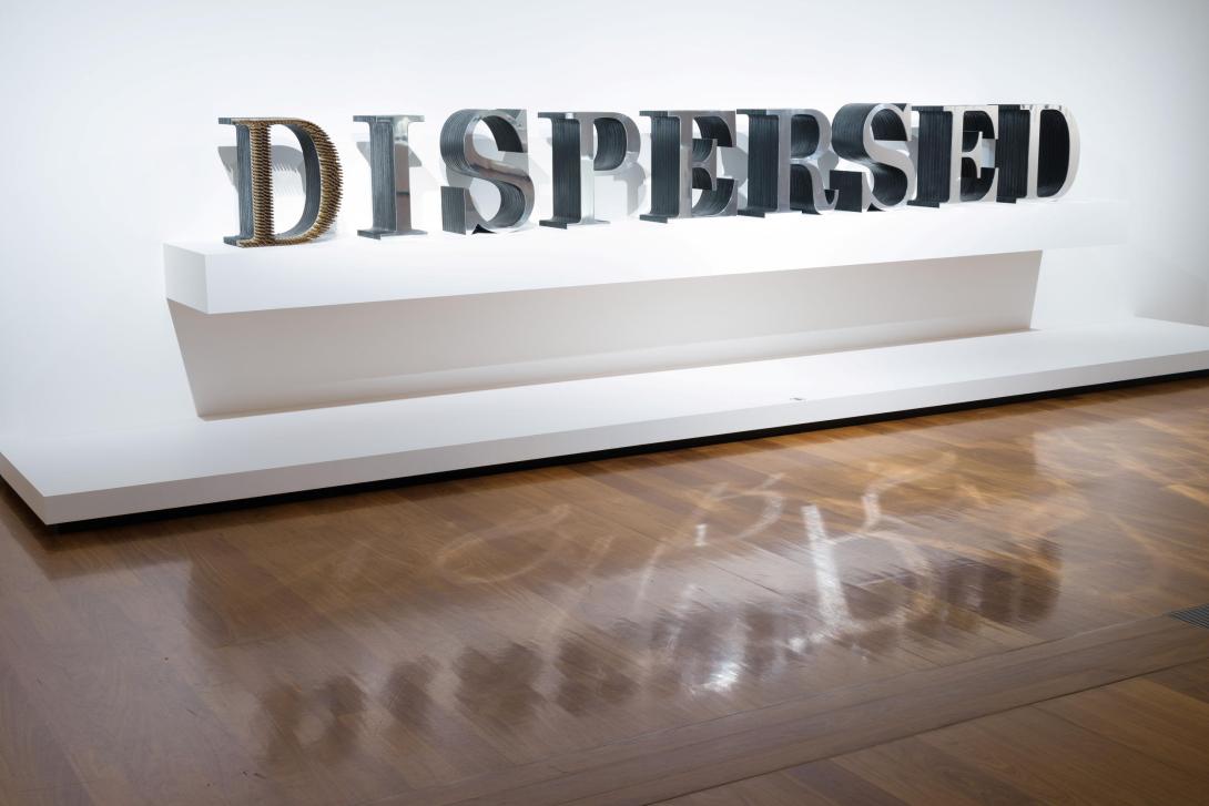 An installation view of a sculptural work that spells out the word 'DISPERSED'