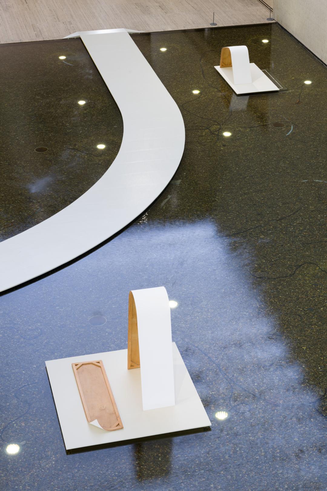 White, minimalist sculptural works installed on white platforms on the water of QAG's Watermall.