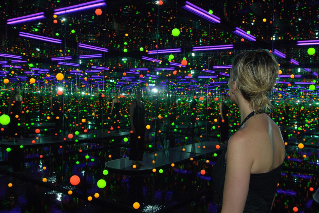 A visitor is seen inside an art installation called an 'inifinity room', which uses light and mirrors to appear to stretch on forever.