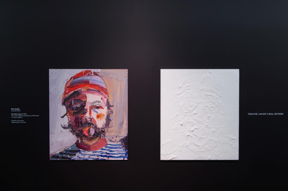 An oil painting of a man wearing a red cap next to a white 3D replica of its impasto textures, installed on a black galllery wall.