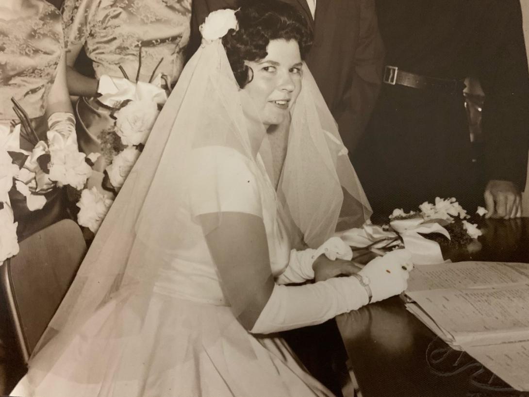 A black-and-white photo of a woman dressed in a 1960s-style bridal gown and veil 