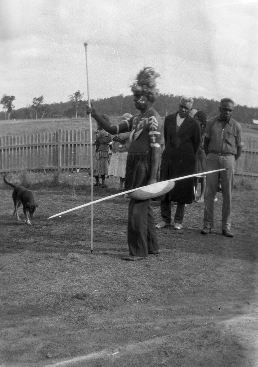 A black-and-white photograph of an Australian Indigenous man wearing ceremonial dress for a funeral