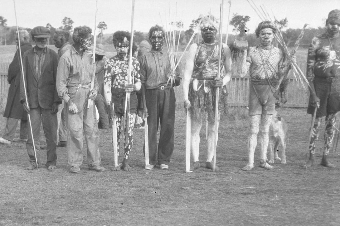 A black-and-white photograph of Australian Indigenous men wearing ceremonial dress for a funeral
