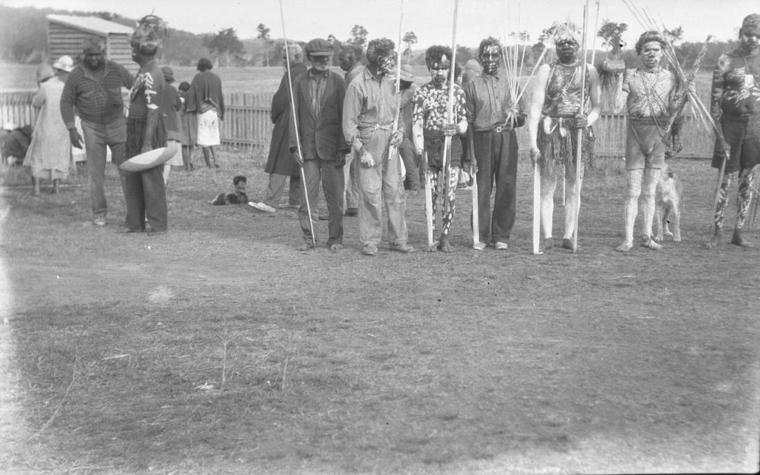 A black-and-white photograph of Australian Indigenous men wearing ceremonial clothes and bodypaint for a funeral