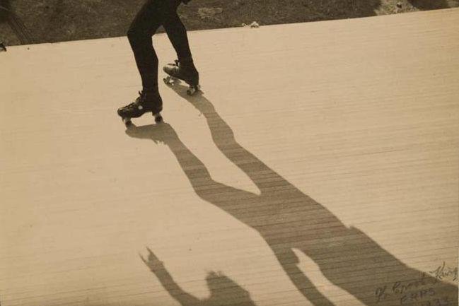 A sepia-toned photograph in which the shoes and shadow of a rollerskater are visible