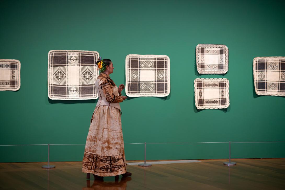 Rosanna Raymond performs within ’sis: Pacific Art 1980–2023’, pictured here with works by Jaki-ed weavers, GOMA, August 2023 / Collection: QAGOMA / © The artists / Photograph: C Callistemon, QAGOMA