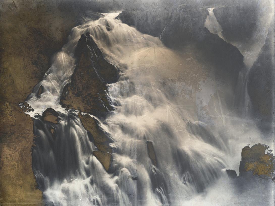 The rapids of an abstracted, sepia-toned waterfall, as seen from above