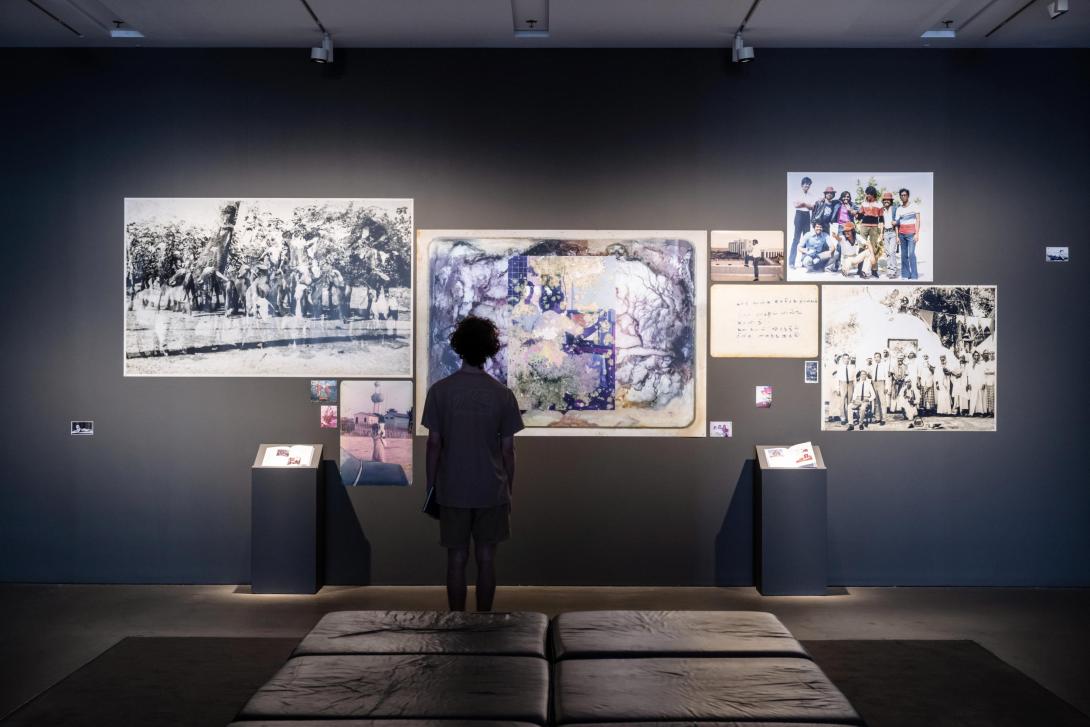 Works installed salon-style in a darkened gallery space