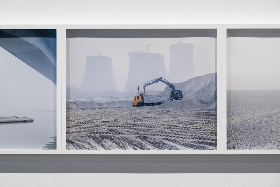 A close-up installation view of photographs installed in white frames on a gallery wall