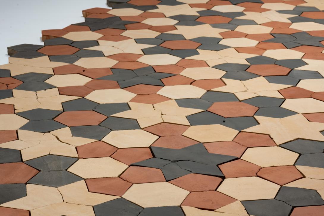 A top-down view of a sculptural work made of tessellated bricks in earth colours