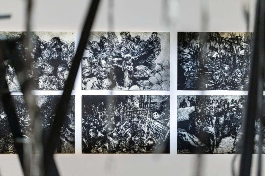 Sombre-toned prints depicting scenes from war, installed on a white gallery wall