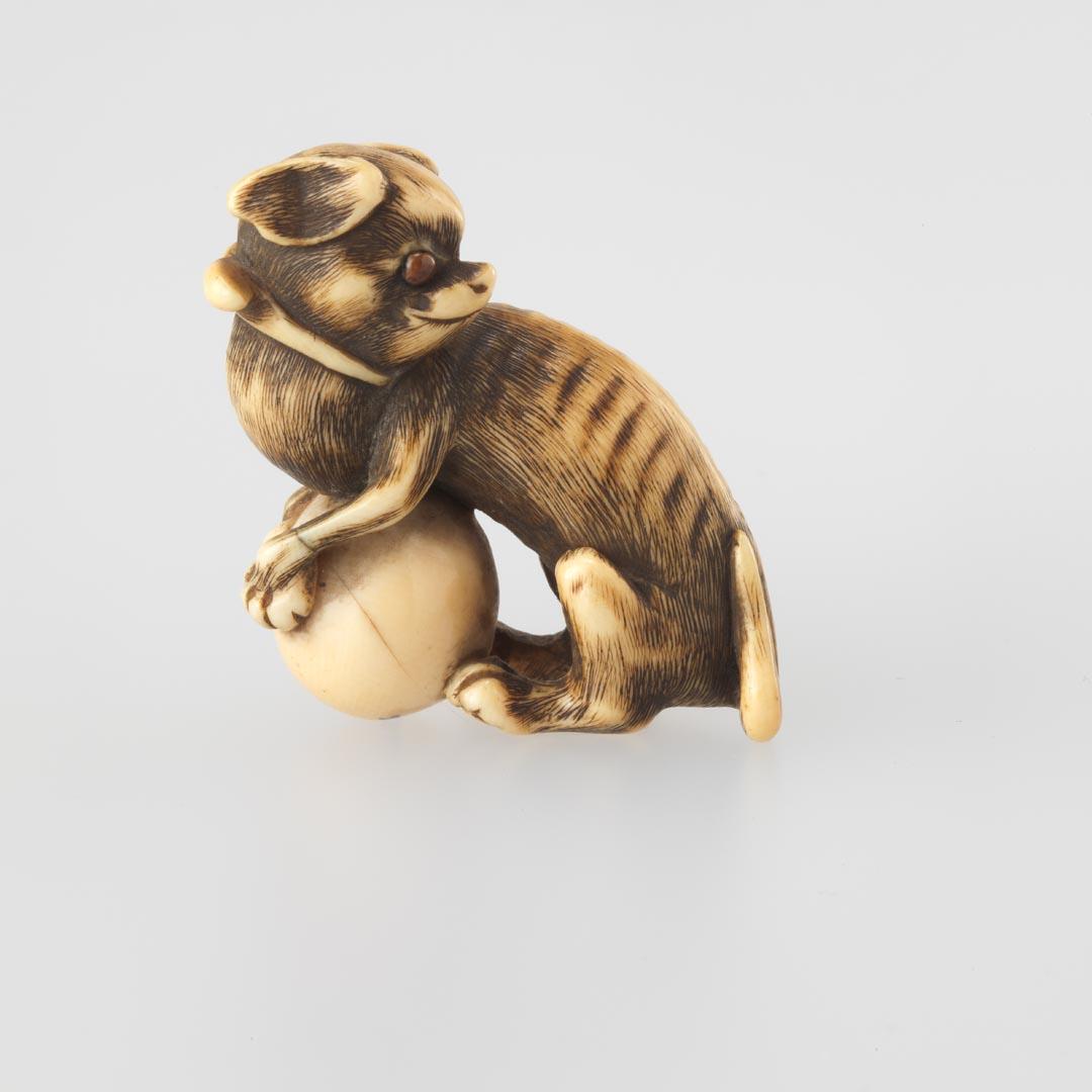 Artwork Netsuke:  (dog with ball) this artwork made of Carved ivory with inset eyes, created in 1800-01-01