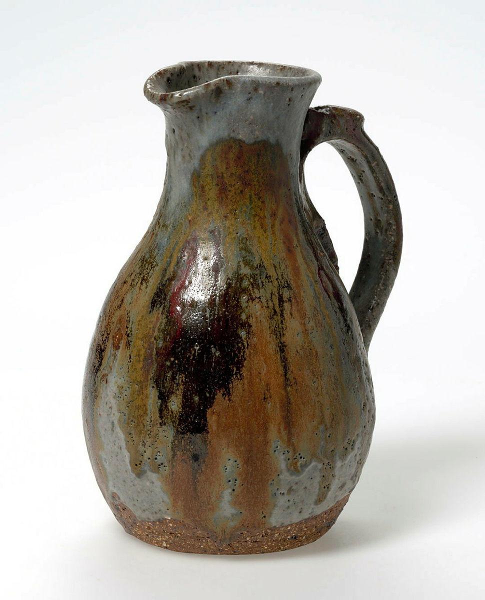Artwork Jug this artwork made of Earthenware, reddish clay with high grog content, thrown, with irregularly applied handle with running and pitted grey, red and brown glazes, created in 1960-01-01