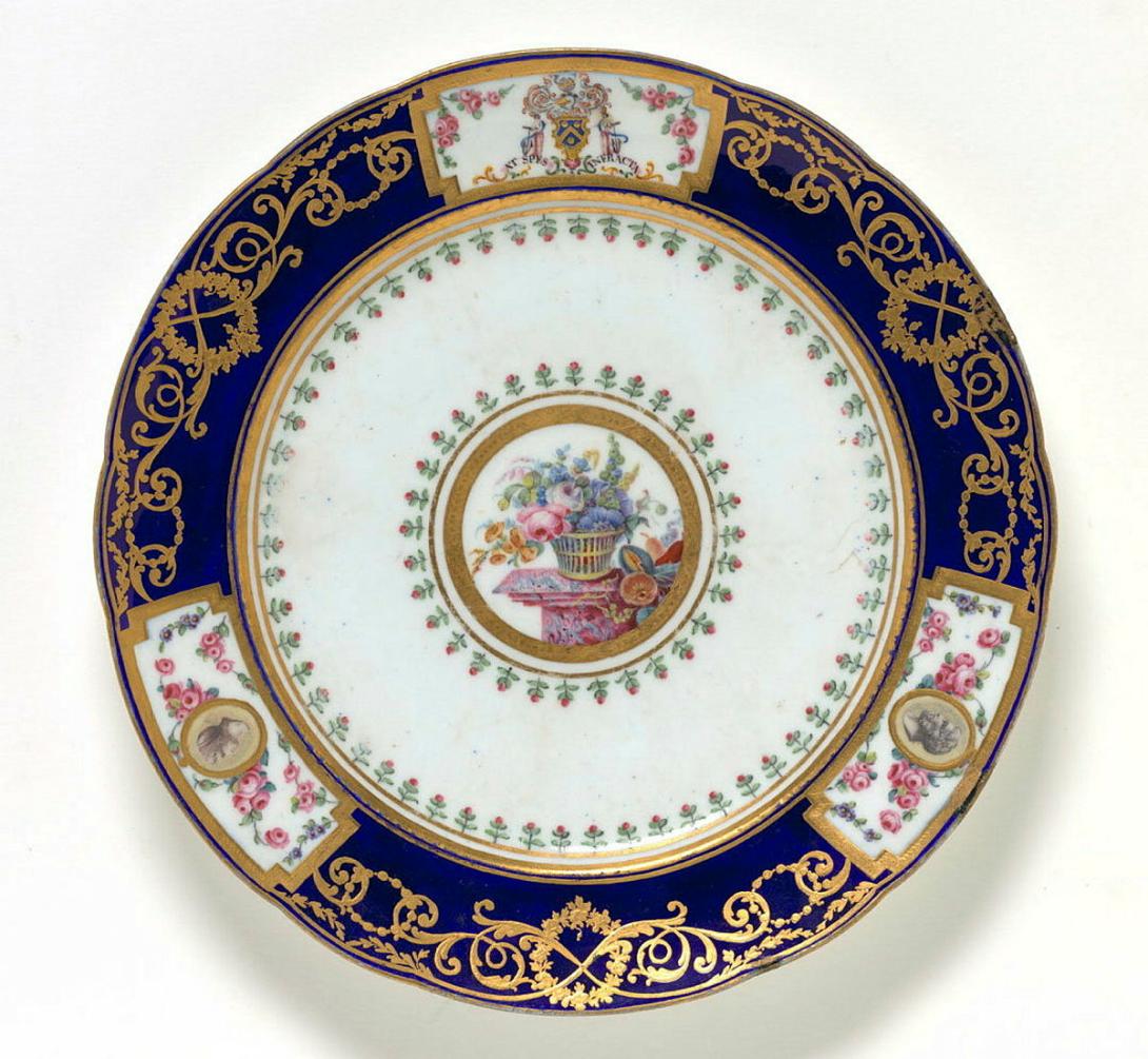 Artwork Armorial plate (from the Hope Service) this artwork made of Soft-paste porcelain, lobel pate with bleu roi border reserving three rectangular segments, two with cameos and the other with a coat of arms above a motto.  Gilt embellishments, created in 1770-01-01