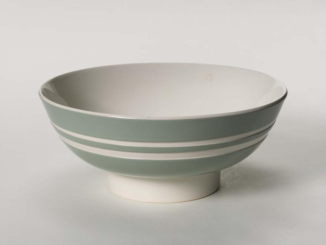 Artwork Footed bowl this artwork made of Earthenware, white bodied clay thrown and dipped in celadon slip.  Incised with two lines of engine turning with clear glazes