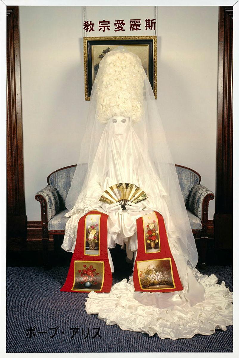 Artwork Official portrait of H.D.H. Pope Alice from the Mu Consulate 1996 
Photographic performance: The Windsor Room, Brisbane City Hall; 
camera Nat Paton this artwork made of Colour photographic transparency and self-adhesive lettering on light box, created in 1996-01-01