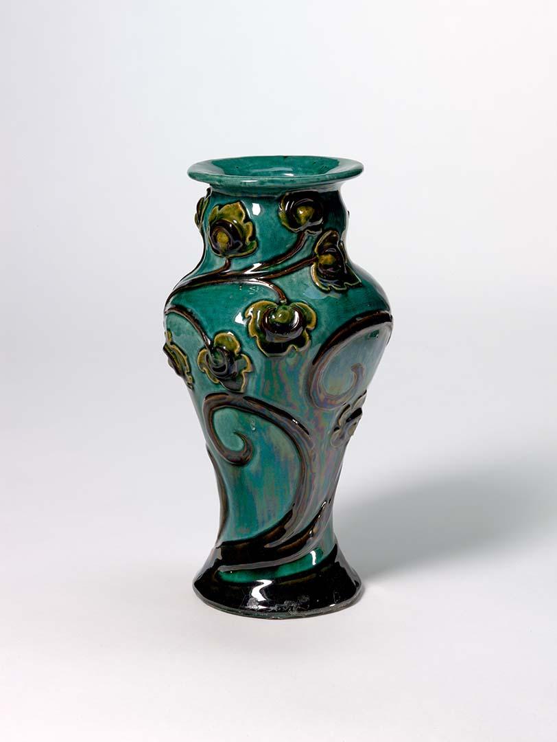 Artwork Vase: (art nouveau) this artwork made of Earthenware, handbuilt with foliate motif applied with brown slip and blue-green glaze