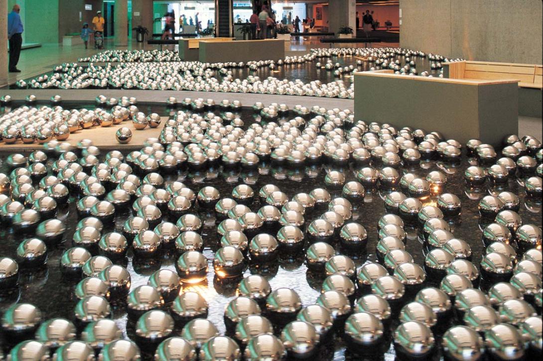 An installation view of a work installed in the QAG Watermall, in which hundreds of small, shiny silver balls float on the water.
