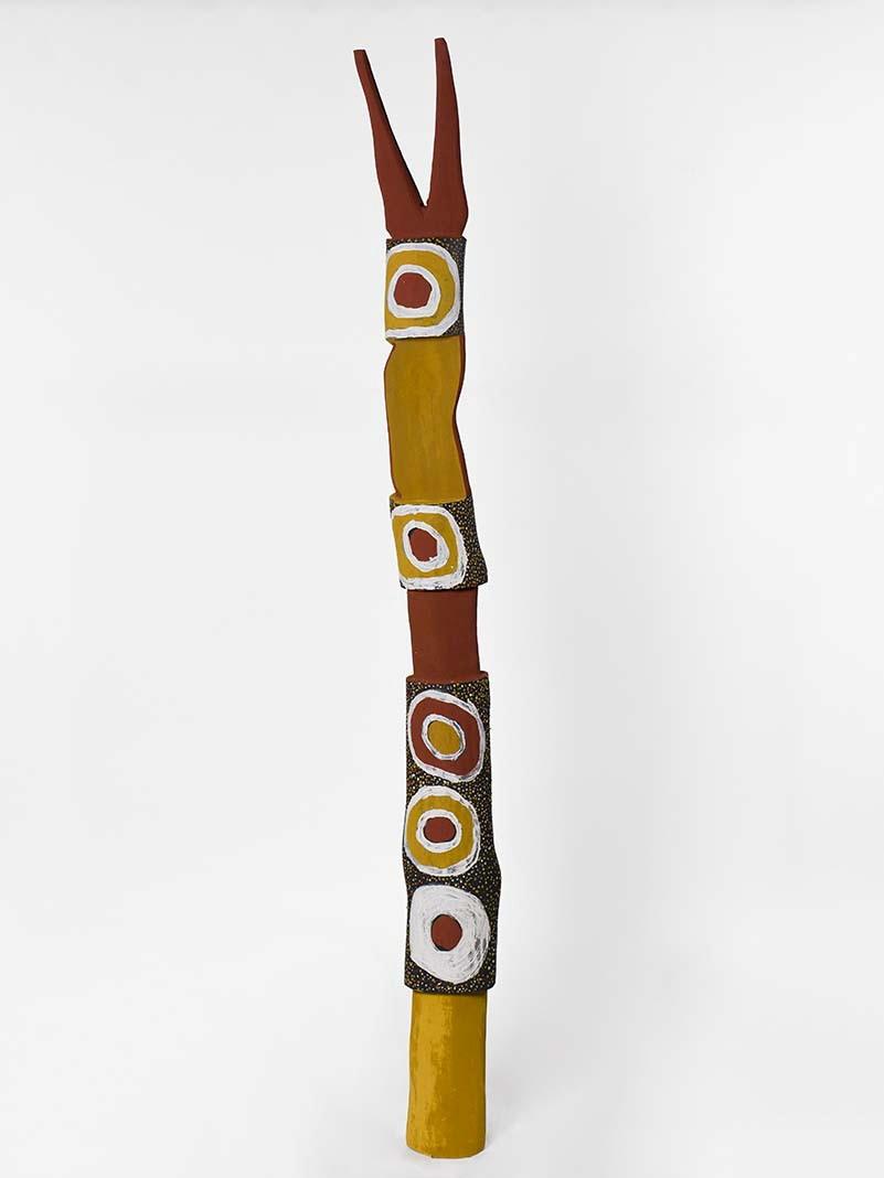 A tall pole (carved ironwood) painted in yellows, whites and reds with natural pigments 
