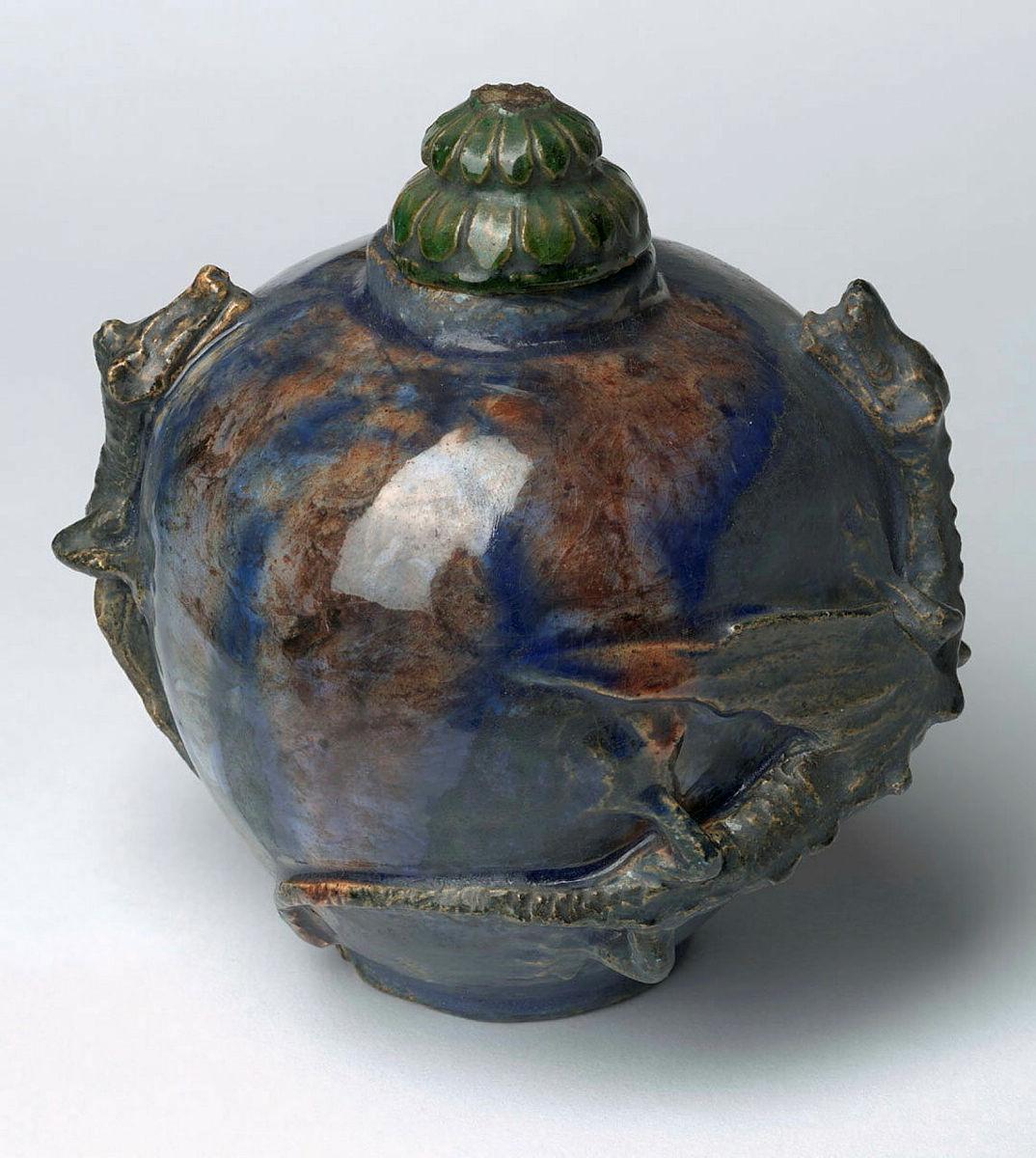 Artwork Covered pot this artwork made of Earthenware, modelled with two winged dragons encircling the rim with blue and bronze glazes, created in 1919-01-01