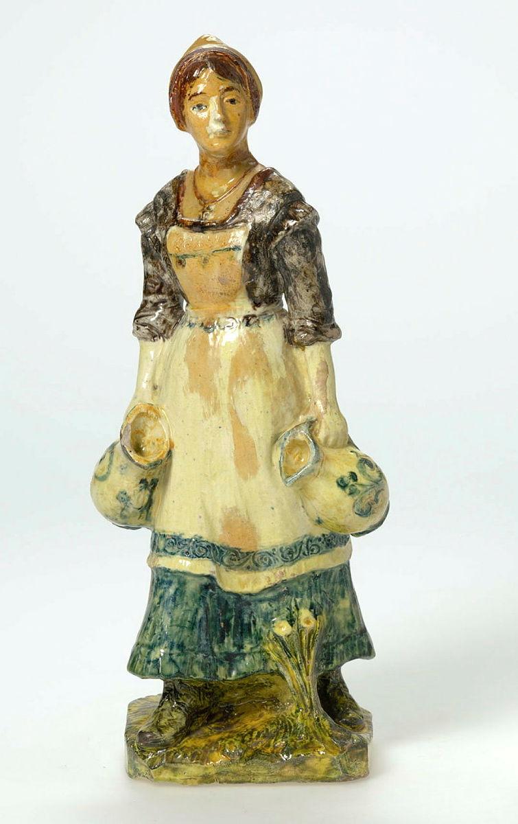 Artwork Milkmaid this artwork made of Earthenware, modelled in the figure of a woman with bucket, with yellow glaze, created in 1920-01-01