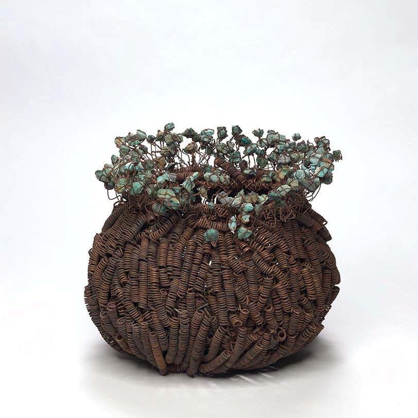 A basket-like structure woven from hand-coiled copper wire and raw copper
