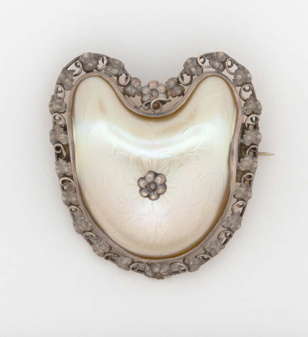 Artwork Silver and mother-of-pearl shell brooch this artwork made of Silver mount with a border of intertwined vine leaves, set with a central carved mother-of-pearl shell piece, decorated with flowers and leaves
