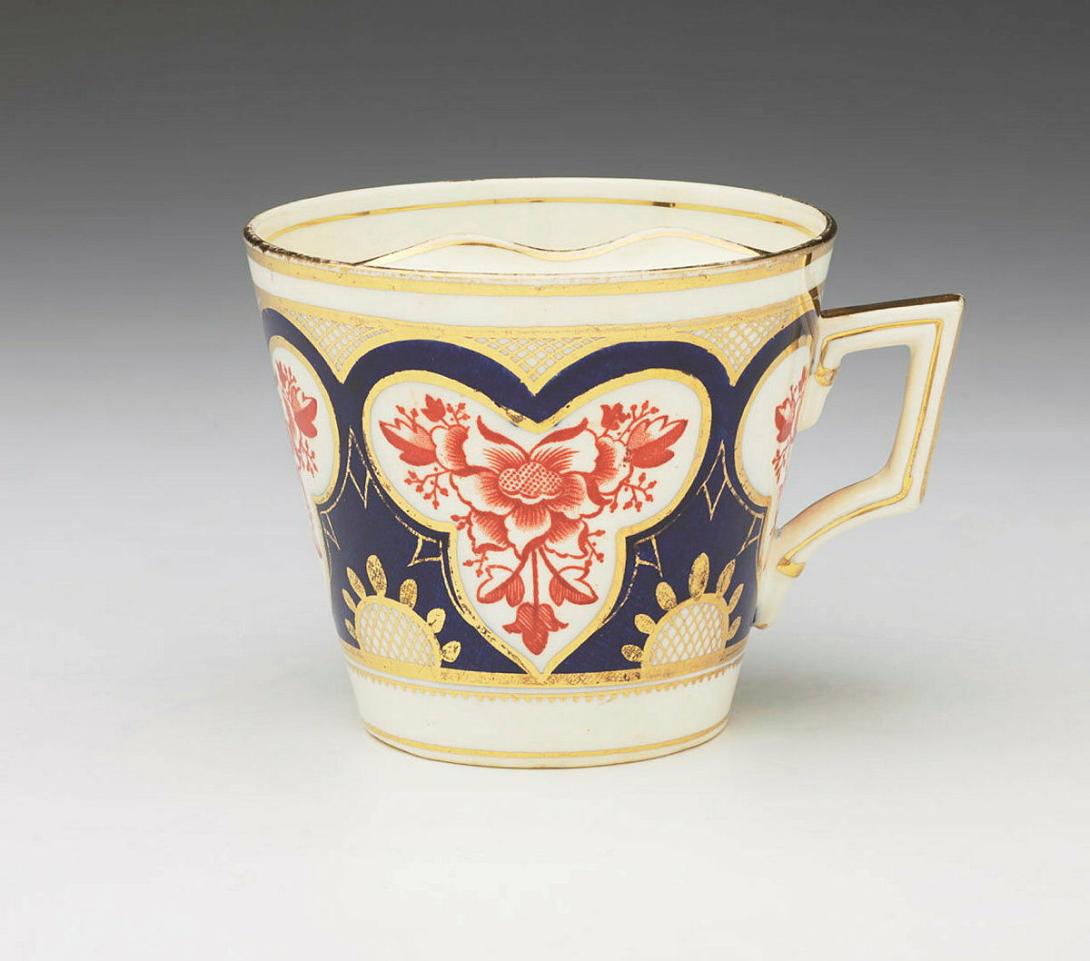 Artwork Moustache cup and saucer this artwork made of Straight-sided cup with moustache protector.  Floral motifs printed in red enclosed within cobalt blue and gilt detailed trefoil shapes, created in 1890-01-01