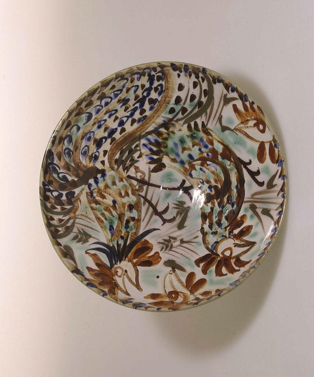 Artwork Bowl:  (Fighting cockerels) this artwork made of Buff earthenware clay, wheelthrown, interior decorated with two cockerels in rust, brown, green, blue and black beneath clear glaze with green exterior, created in 1947-01-01
