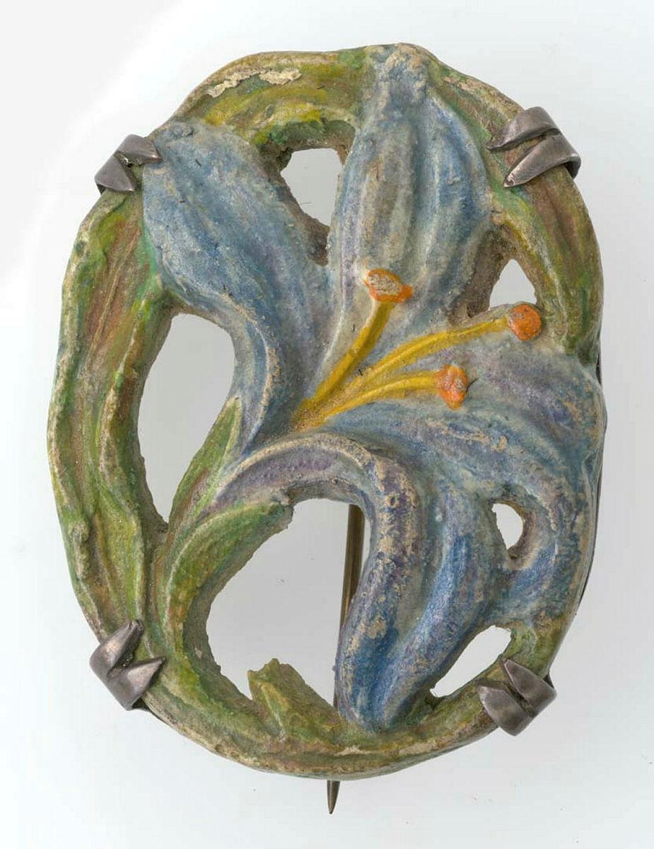 Artwork Brooch this artwork made of Earthenware carved with a lily motif in an art nouveau manner with overglaze colours and mounted in silver, created in 1941-01-01