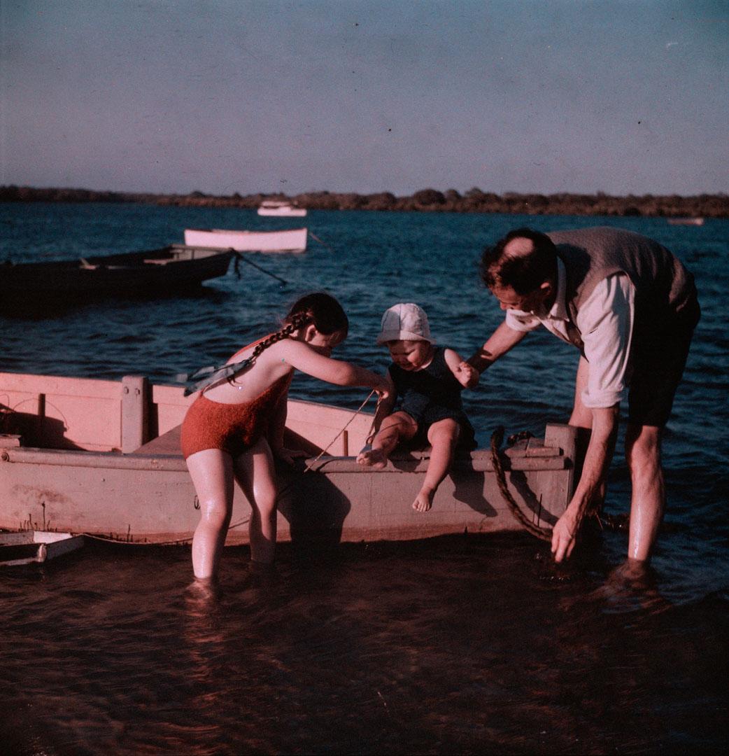 Artwork (J.H. Simmonds and Rosemary holding Margaret sitting on the edge of a boat) this artwork made of Cellulose acetate Dufay colour transparency (originally in a glass mount)