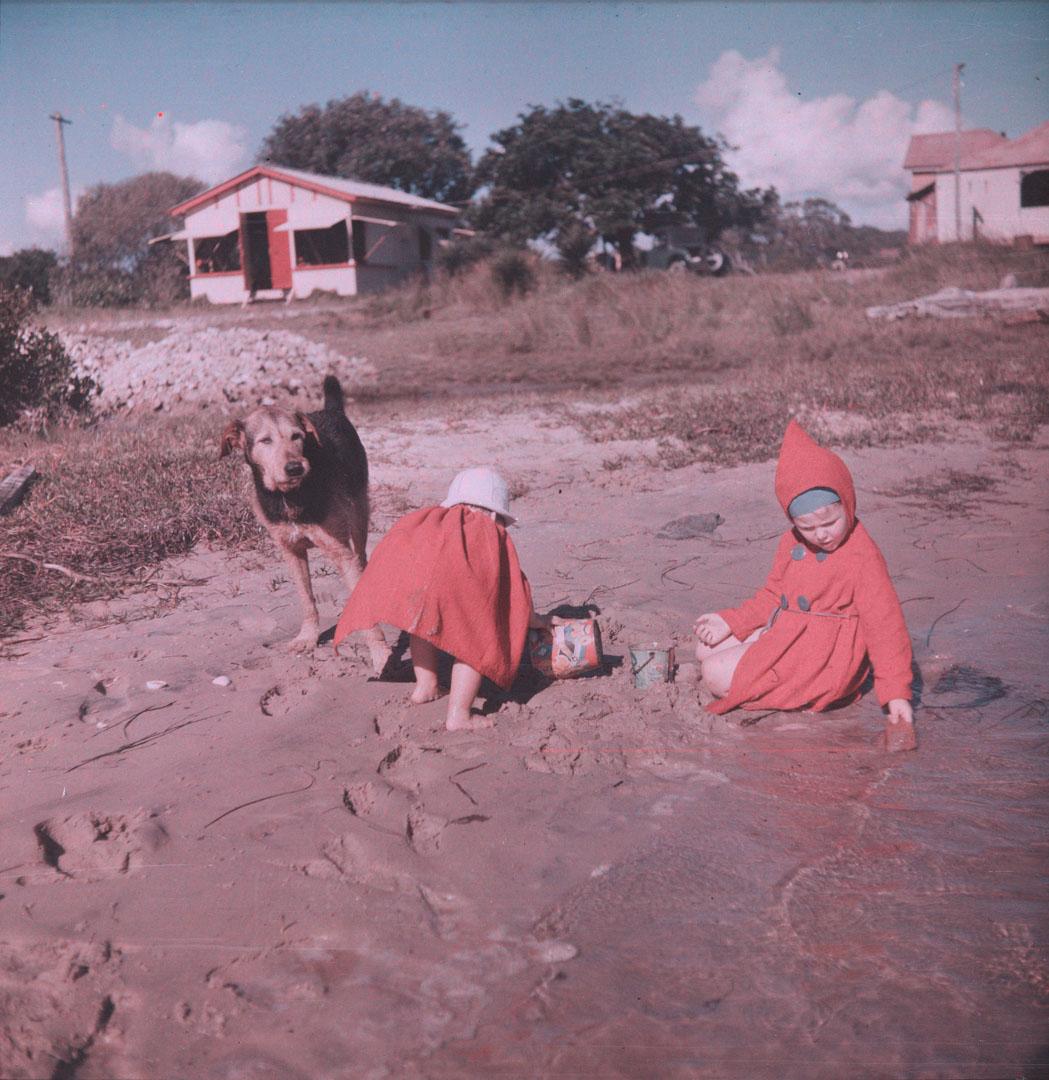 Artwork (Two small girls in red, making sand castles, with a dog) this artwork made of Cellulose acetate Dufay colour transparency (originally in a glass mount), created in 1935-01-01