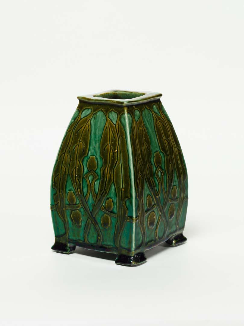 Artwork Slab built vase this artwork made of Earthenware, slab built vase dipped in green slip and incised with a design of gumleaves and nuts. Glazed green blue, created in 1926-01-01
