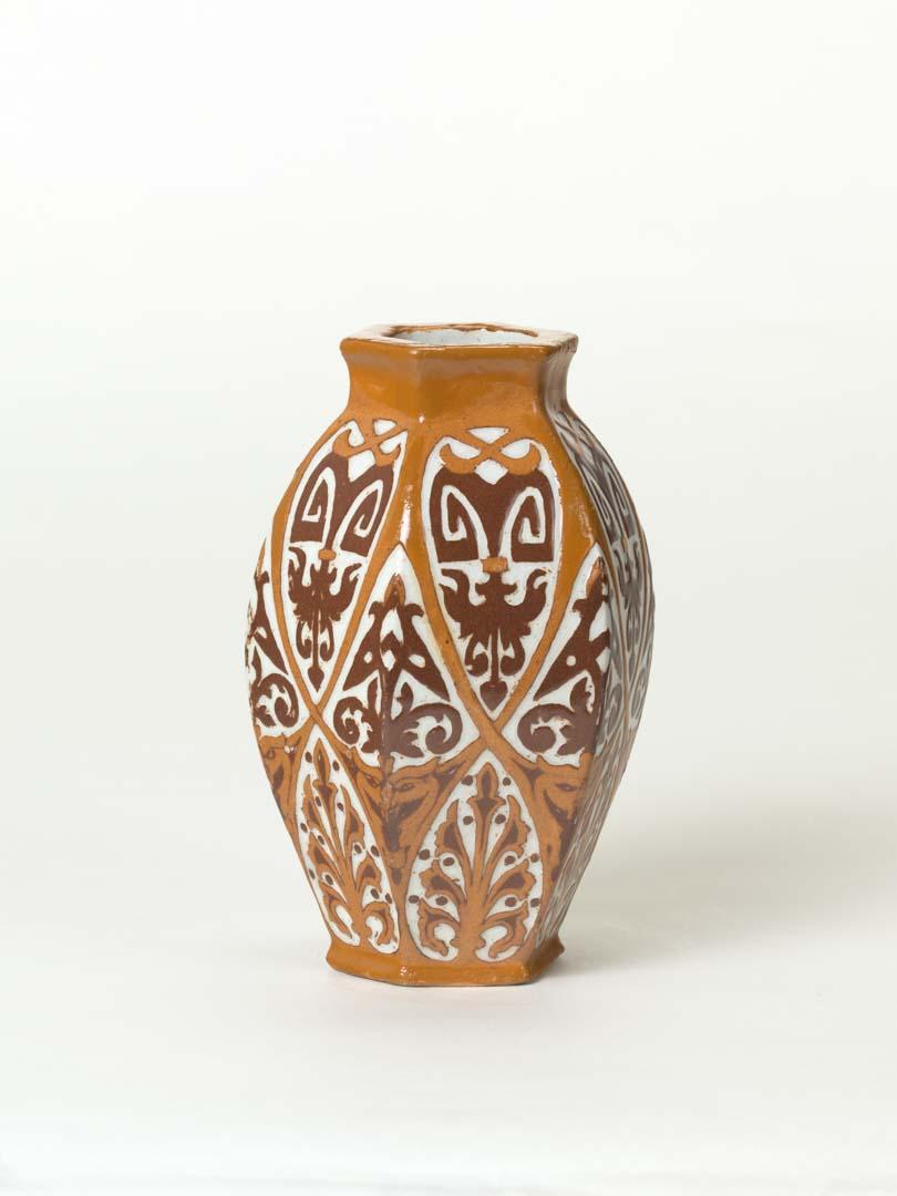 Artwork Double scraffito vase this artwork made of Earthenware, slab built white earthenware dipped in brown and ochre clays and incised with formalised designs in the double scraffito technique. Clear glaze, created in 1928-01-01