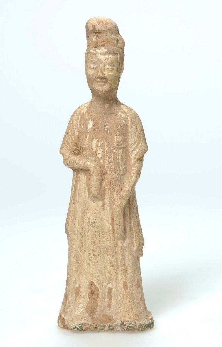 Artwork Tomb figure:  (Female with elaborate hairstyle) this artwork made of Earthenware, modelled with a degraded straw coloured glaze, created in 0618-01-01