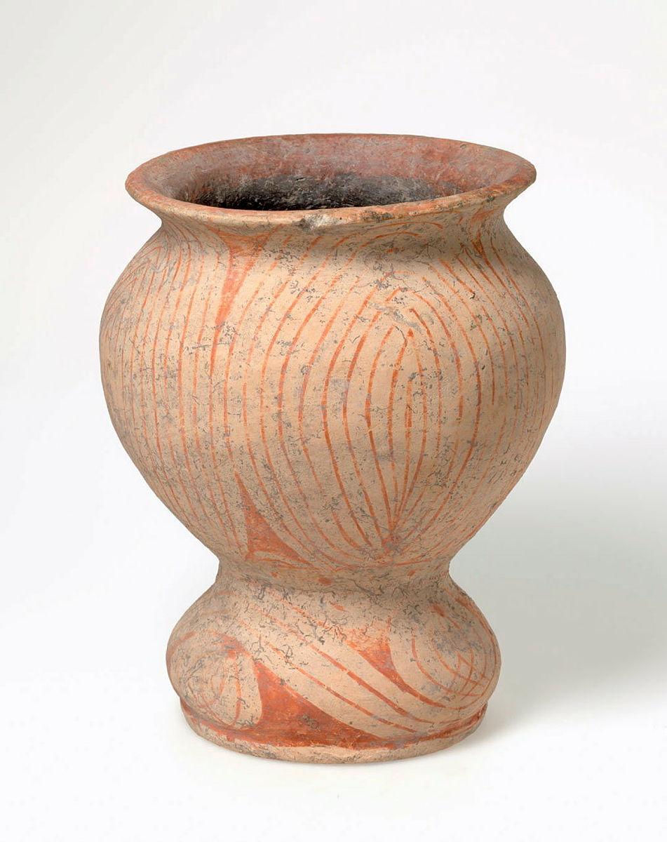 Artwork Storage jar with foot this artwork made of Hand-built buff earthenware body of spherical shape with flaring rim and waisted foot.  Red linear decoration