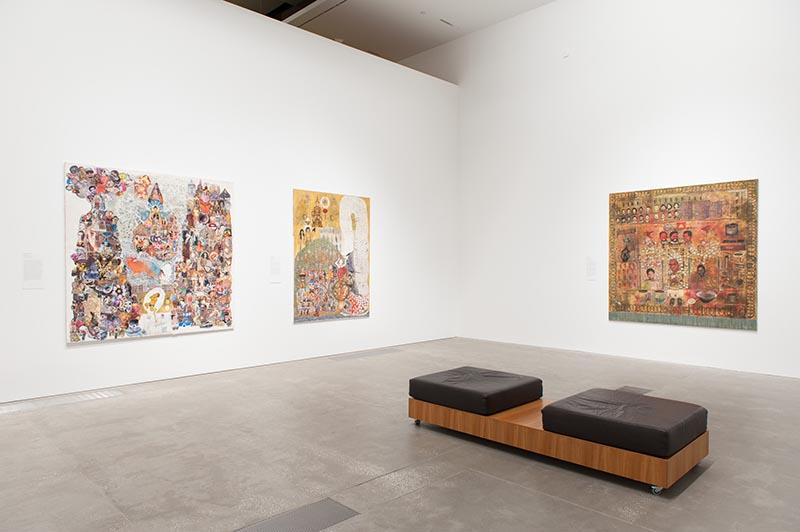 An installation view of works by Leang Seckon hung on white gallery walls with a bench in the foreground.