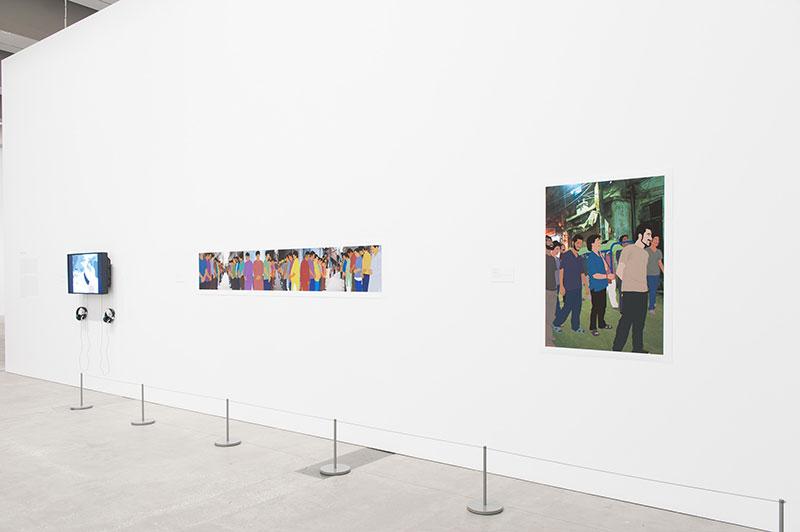 An installation view of colourful works seen at a distance installed on a white gallery wall.