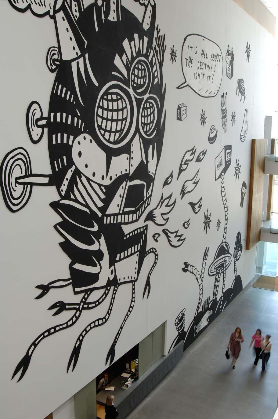 An installation view of an immense wall mural in GOMA's Long Gallery: a black-and-white painting of a fanciful robot breathing fire towers over visitors below.