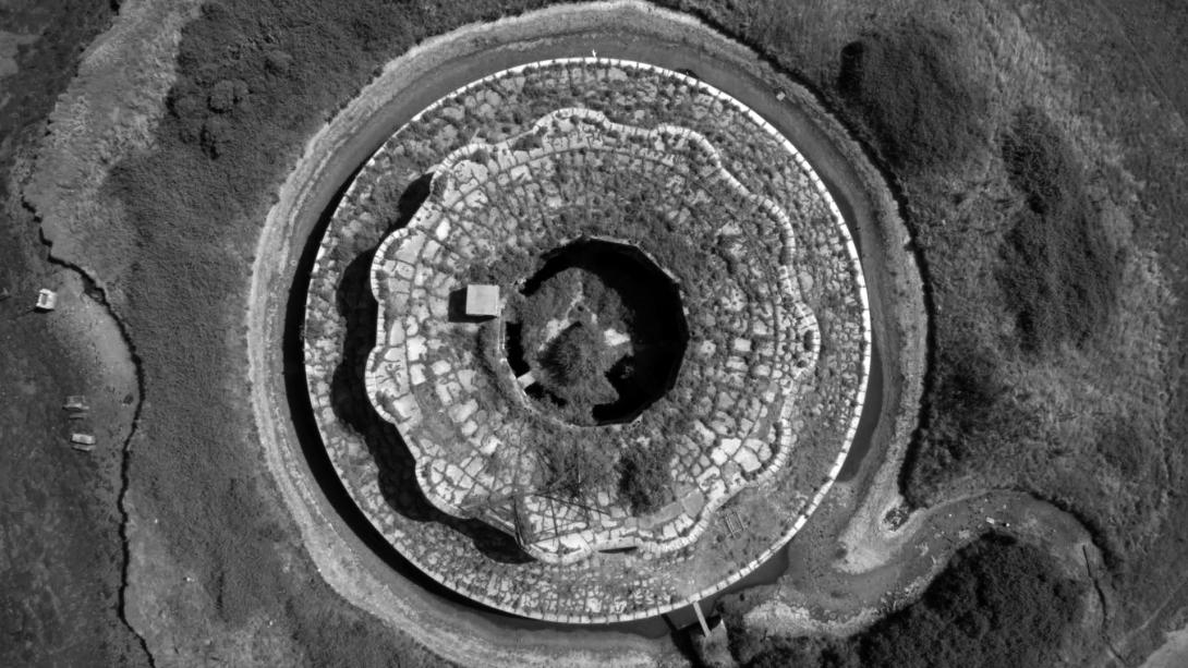An overhead view, in black and white, of a large circular concrete structure.