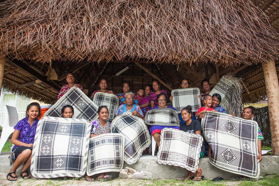 The participants in the Jake-ed weaving workshop hold up their final creations: black-and-white mats with geometric patterns.