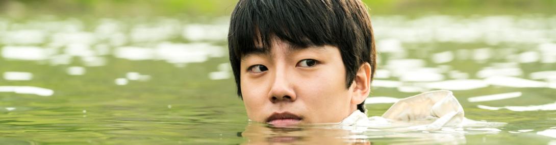 A panoramic still photo of a young man swimming in greenish waters.
