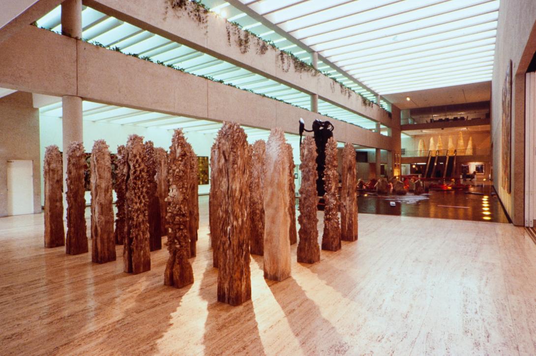 An installation view of a work installed for APT1 in 1993, with sculpted wooden tree-like structures arranged near the Watermall in QAG.