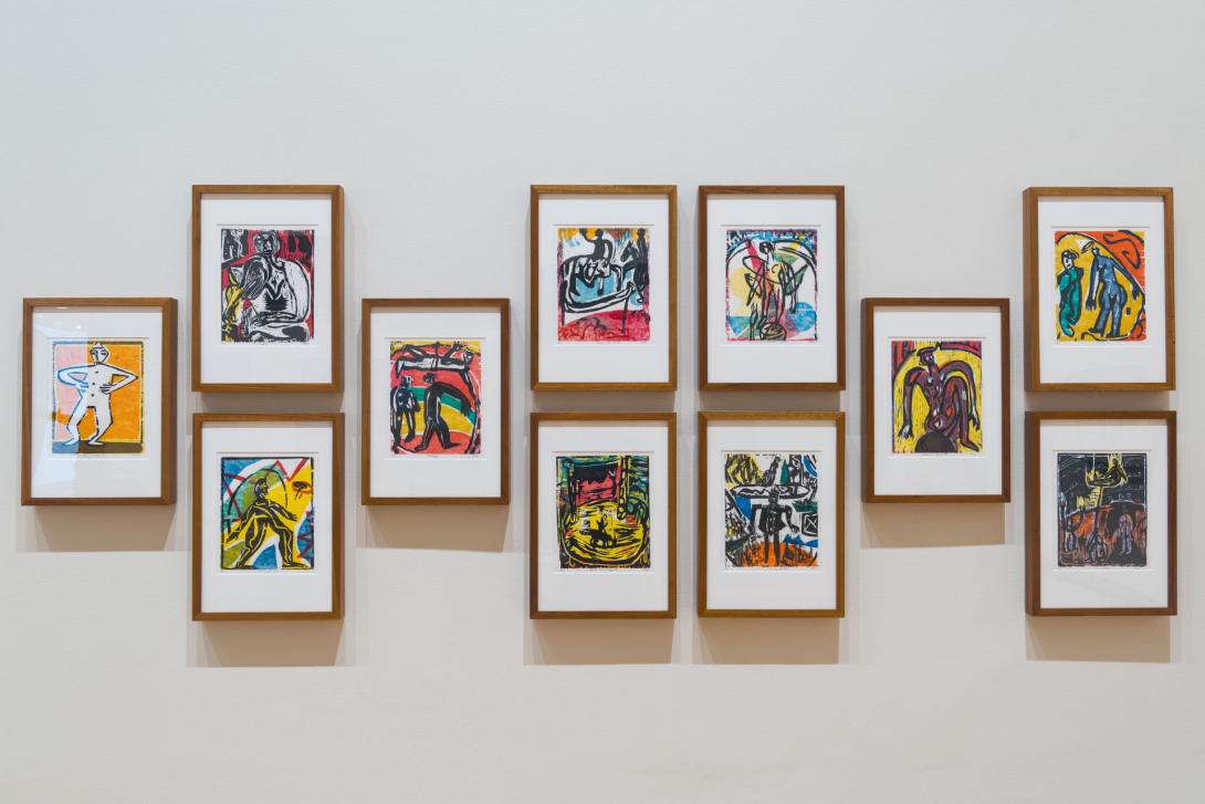An installation view of 11 small, framed colourful woodcuts depicting circus acts.